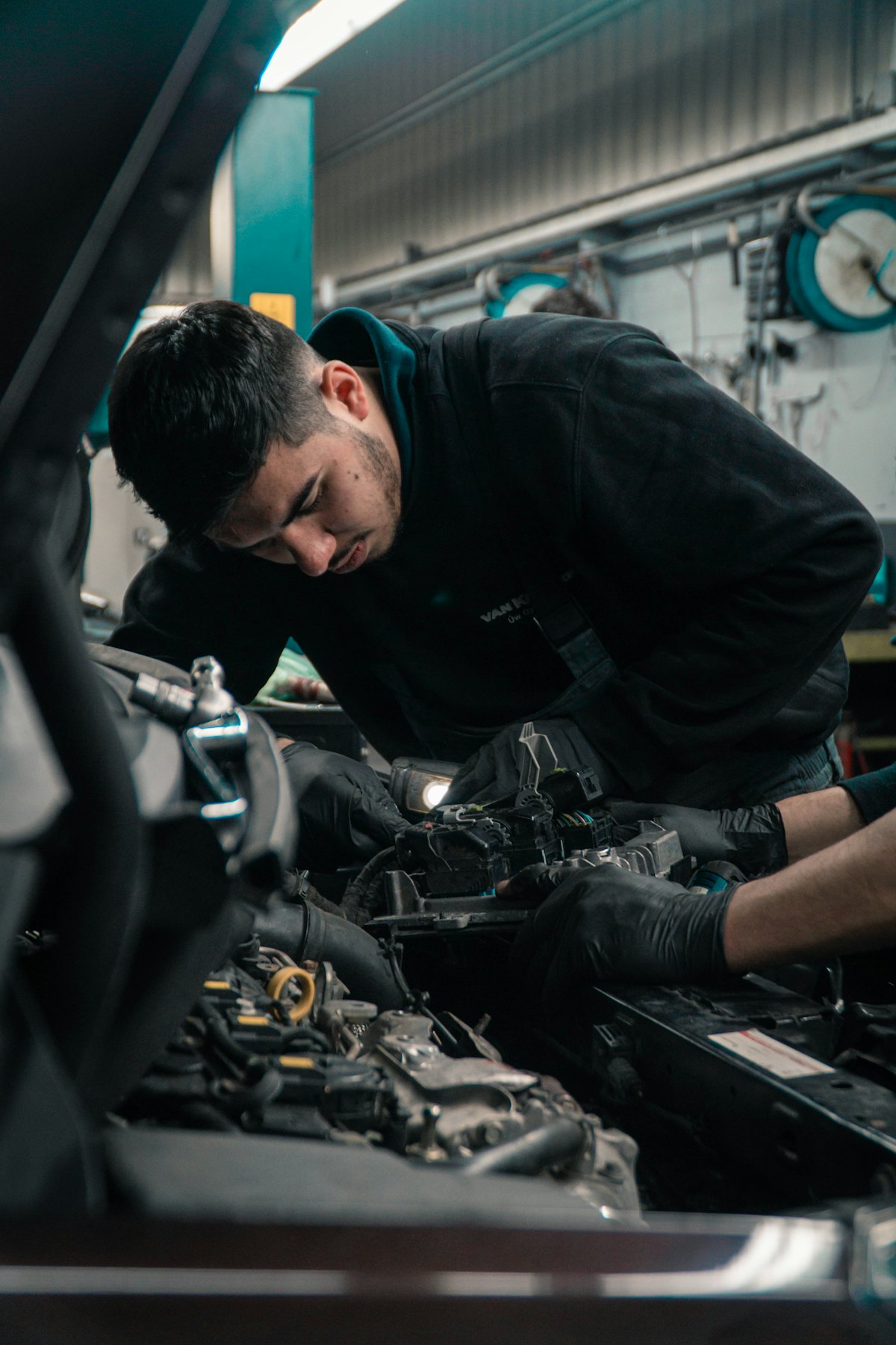 A technician working under the hood in the bay at an auto repair shop
